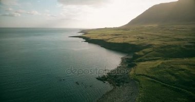 İzlanda'daki su yakınındaki dağ Vadisi üzerinde uçan helikopter. Çayır ve deniz kıyısında havadan görünümü.