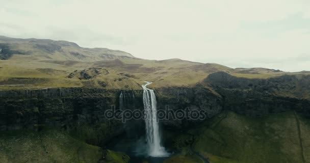 Luchtfoto naar de vallei van de bergen. De rivier stroomt door de heuvels en vervolgens naar beneden valt. Seljalandsfoss waterval. — Stockvideo