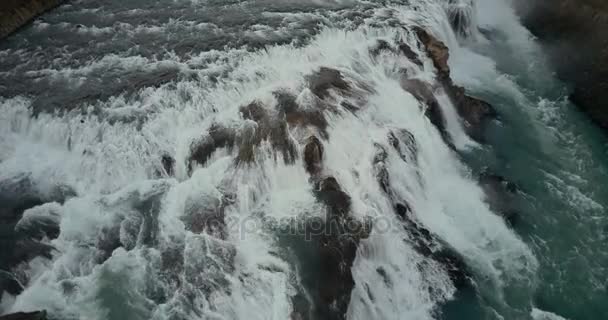 Luftaufnahme des turbulenten Wasserflusses in den Klippen. Hubschrauber fliegt über den mächtigen Wasserfall in Island. — Stockvideo