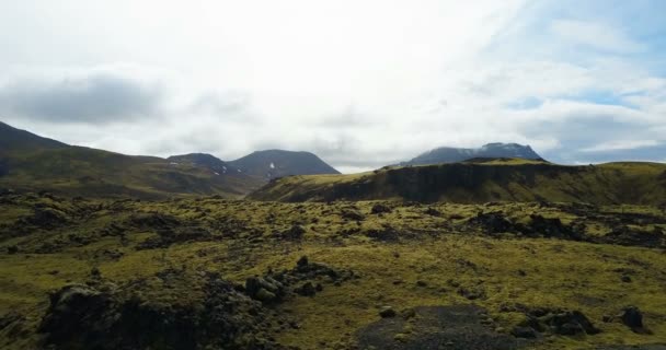 Aerial view of the lava field in Iceland. Copter flying over the green mountains with moss in cloudy day. — Stock Video