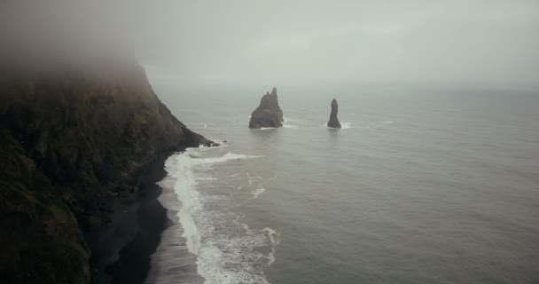 Copter vliegt over het mooie zwarte vulkanische strand en troll tenen kliffen in IJsland. Landschap van zee, mist en golven. — Stockvideo