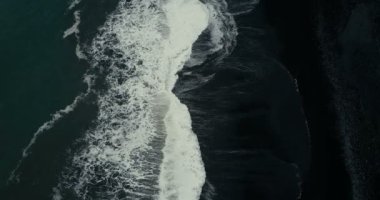 İzlanda'daki siyah volkanik plaj kıyısına gelen köpük ile güçlü dalga hava Üstten Görünüm.