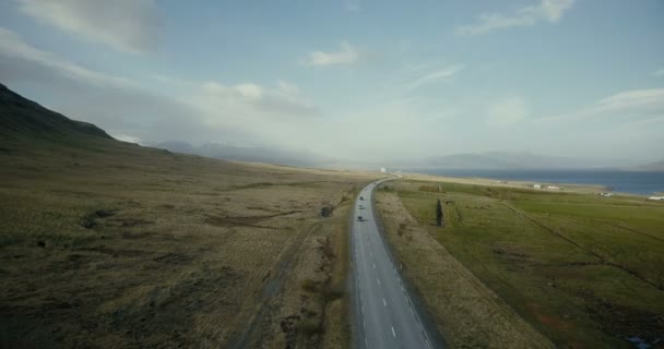 Luchtfoto van de Oceaan en bergen vallei. Auto's die rijden op de weg van het platteland met veld rond. — Stockvideo