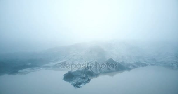 Vista aérea del glaciar Merdalsjokull con ceniza volcánica en Islandia. Copter volando cerca del iceberg en el lago, en la niebla . — Vídeo de stock