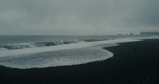Flygfoto över den vackra svarta vulkaniska stranden på Island. Vilda vågor med skum kommer på stranden i mulen dag. — Stockvideo