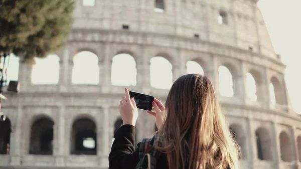 Молодая брюнетка турист, исследующий Колизей в Риме, Италия. Женщина фотографирует, использует смартфон . — стоковое фото