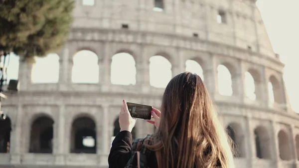 Joven turista morena explorando el Coliseo en Roma, Italia. Mujer toma la foto de la vista, utiliza el teléfono inteligente . — Foto de Stock