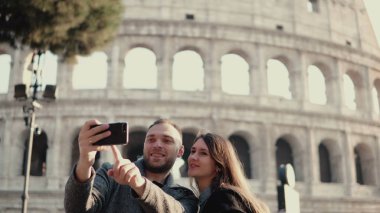 Roma, İtalya, Colosseum civarındaki selfie fotoğrafı çekmek Smartphone kullanarak mutlu genç bir çift. Erkek ve kadın tatiller.