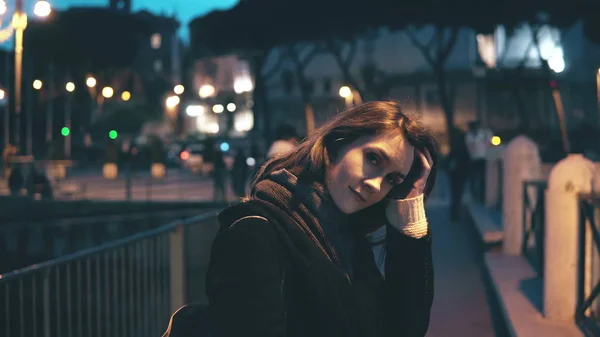 Ritratto di giovane bella donna che guarda la macchina fotografica e fa i capelli. La ragazza si gira, se ne va in città la sera . — Foto Stock