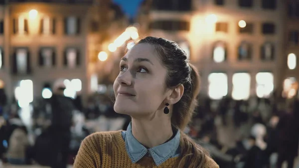 Retrato de jovem mulher bonita de pé no centro da cidade à noite. Estudante menina olha para a câmera, sorrindo . — Fotografia de Stock