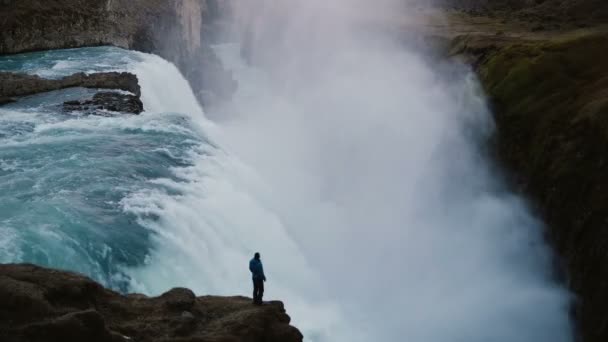 Prachtig uitzicht over de man staande op de rand van de rots en kijkt op de Gullfoss waterval in IJsland. — Stockvideo