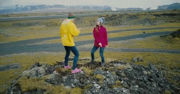 山トップの場合に 2 つの女性の近くを飛んでいると、一緒にダンスをドローンします。観光客がアイスランドの溶岩フィールド. — ストック動画