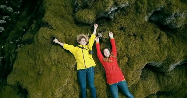 Copter fliegt von Nah- bis Weitschuss hoch. twp glückliche Touristinnen ruhen sich auf dem Lavafeld in Island aus. glückliche Weibchen — Stockvideo