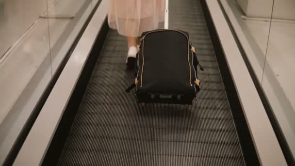 Vue rapprochée de la jeune femme avec une valise debout sur l'escalier roulant de l'aéroport. Hipster femelle prête à partir en voyage . — Video