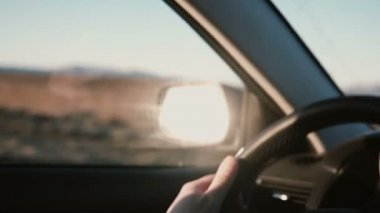 Arabanın içinde kırsal çöl yol inbeautiful sunset bulvarında görüntüleyin. Erkek görünümünü yakın çekim tekerlek üzerinde eller.