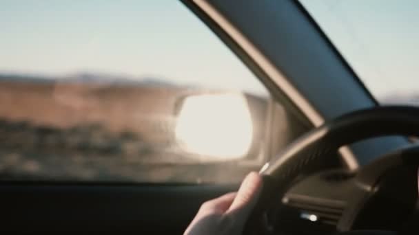 Vista dentro del coche en el campo camino del desierto enhermosa puesta de sol. Vista de cerca de las manos masculinas en el volante . — Vídeo de stock