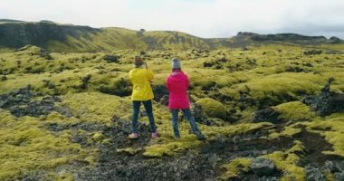 İzlanda'daki lav sahada ayakta ve manzara zevk iki kadın hava görünümünü. Turistler yürüyüş sonra.
