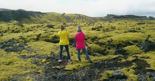 Flygfoto över två kvinna stående på fältet lava i Island och njuta av landskapet. Turister efter vandring. — Stockvideo