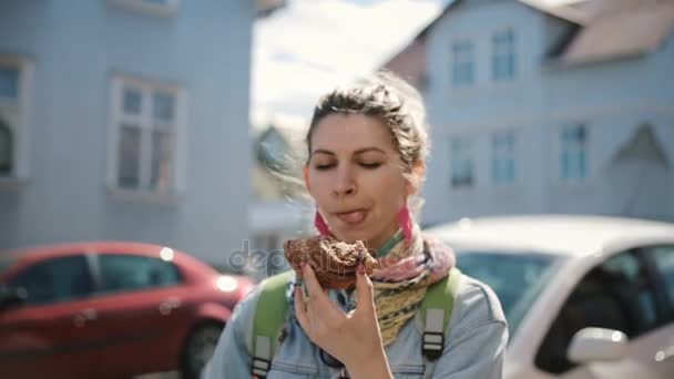 Retrato de mulher atraente bonito em pé na rua e comer o pão assado. Fome feminino fazer uma pausa em fast food . — Vídeo de Stock