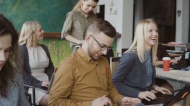 Modern ofis eğitim dinleme genç iş ekibi. Erkek ve kadın dizüstü bilgisayar ile tablet gülmek ve notlar yapar.