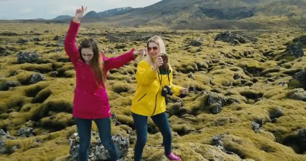 Luchtfoto van de twee gelukkige vrouw staande op de rots en plezier, dansen. Lava veld in IJsland gedekt moss. — Stockvideo