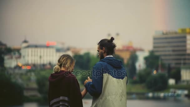 Back view of happy couple looking on the city panorama on sunset. Man hugs woman and enjoying the downtown in evening. — Stock Video
