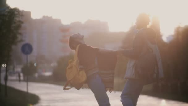 Jovem casal bonito se divertindo na chuva. Homem e mulher felizes virando-se, beijando e abraçando no pôr do sol . — Vídeo de Stock