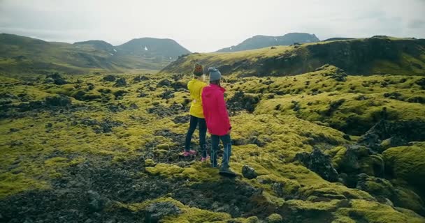 Luftaufnahme zweier Frauen, die auf den Lavafeldern in Island spazieren gehen. Touristen genießen die Landschaft, erkunden das Gebiet — Stockvideo