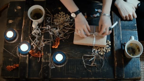 Vista dall'alto della giovane coppia seduta a tavola e che beve tè. Giovane donna che apre il regalo di Natale quello che l'uomo ha dato — Video Stock