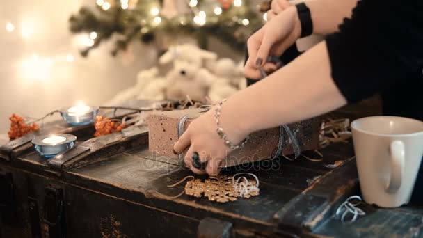 Vue rapprochée du jeune couple assis à la table et ruban de cravate sur la boîte cadeau de Noël en soirée . — Video