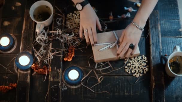 Vista de cerca superior de las manos femeninas que decoran la caja de vacaciones. Mujer joven preparando regalo de Navidad a un amigo . — Vídeos de Stock