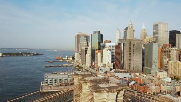 Вид с воздуха на Манхэттен в Нью-Йорке, Америка. Беспилотник летит над Ист-Ривер, Бруклинский мост и машет на ветровом флаге — стоковое видео