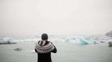 Seyahat gencin Jokulsalon içinde ayakta arkadan görünüm lagün İzlanda'daki buz ve fotoğraf og buzullar smartphone çekmek..