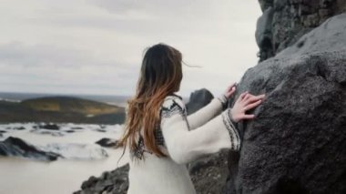 Dağlar, İzlanda'daki Vatnajokull buz lagoon yakınındaki kayalarda yürürken genç explorer kadın arkadan görünüm.