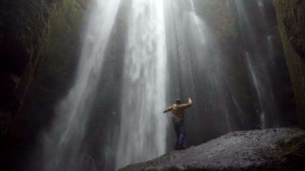 Giovane viaggiatore che cammina vicino alla potente cascata Gljufrabui in Islanda. Salto maschile di gioia e felice . — Video Stock