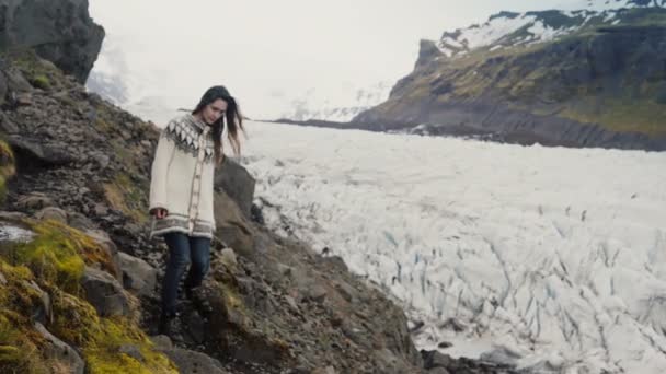 Unga resande kvinnan gå genom klipporna i bergen, att utforska Vatnajokull glaciärer lagunen på Island. — Stockvideo