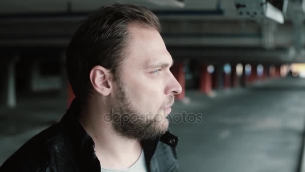 Portrait of young handsome man standing on parking place alone, turning had, looking at camera and smiling. — Stock Video