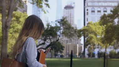 Genç belgeleri holding ve New York, Amerika smartphone kullanarak iş için yürüyüş işkadını meşgul.