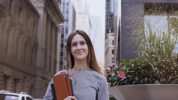 Retrato de jovem bela empresária bem sucedida perto de prédio de escritórios em Nova York, América. Feminino detém documentos . — Vídeo de Stock