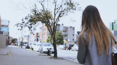 Arkadan görünüşü ile sokakta yürürken ve smartphone, kullanarak genç kadın browsing belgili tanımlık enterne. Ağır çekim.
