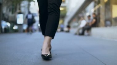 Kadın ayakları ile şehir merkezine yürüyüş yakın çekim görünümü. İşkadını topuklu ayakkabılar giyiyor. Ağır çekim.