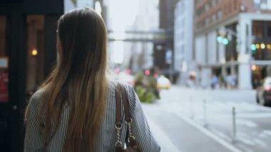 New York, Amerika Caddesi yürüyen genç esmer kadın arkadan görünüm. Rüzgarda sallayarak saç. Ağır çekim.