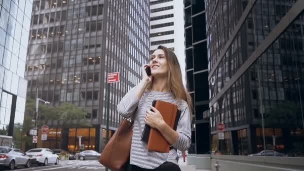 Fiatal üzletasszony, séta keresztül a pénzügyi district of New York, Amerikai, és beszél a mobiltelefon. Lassú mozgás — Stock videók