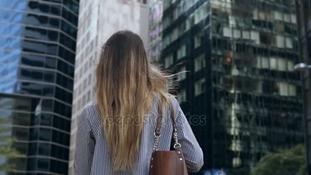 Vue de dos de la jeune femme d'affaires tenant les documents et allant à l'immeuble de bureaux à New York, États-Unis. Mouvement lent . — Video