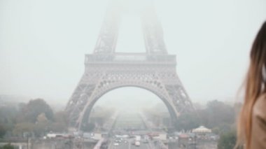 Fransa'nın Paris, Eyfel Kulesi yakınındaki şehir merkezindeki yürüyen genç kadın. Erkek üstünde hareket eden telefon aramayý cevaplar.
