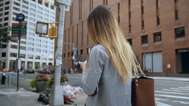 Pengusaha wanita muda yang memegang dokumen dan berjalan di distrik keuangan, menggunakan smartphone. Gerakan lambat . — Stok Video