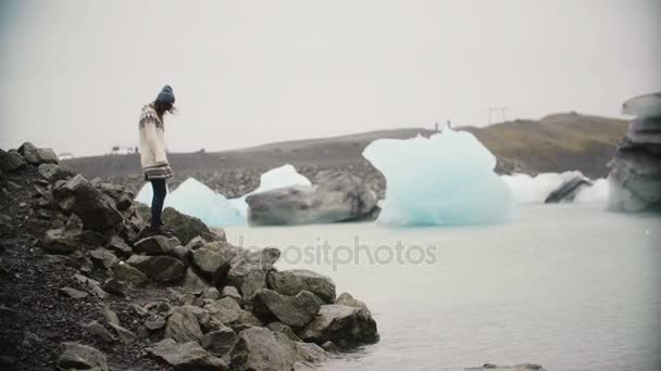 Jeune femme séduisante à lopapeysa debout dans la lagune de glace. Tourisme explorant la célèbre vue de l'Islande seule . — Video