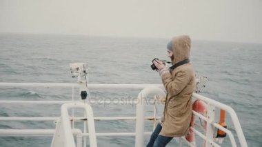 Teknenin gemide duran ve çekim kamera bulutlu günde genç kadın gazeteci.