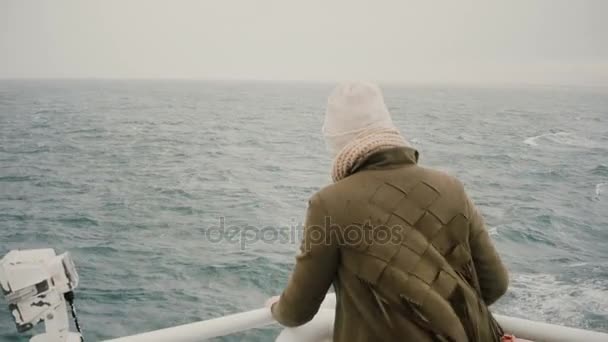 Rückansicht einer jungen blonden Frau, die auf dem Schiff steht und wehmütig auf das Meer blickt und die Insel erkundet. — Stockvideo