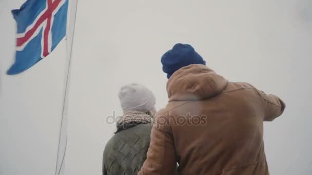 Vue arrière du jeune couple voyageant sur le navire avec le drapeau islandais ensemble. Homme et femme regardent la mer ensemble . — Video